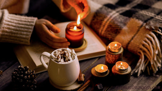 A cozy reading sancutary set up. Candles are being lit by someone wearing a comfy wool sweater with an open book and mug filled to the brim and a plaid, wool blanket.