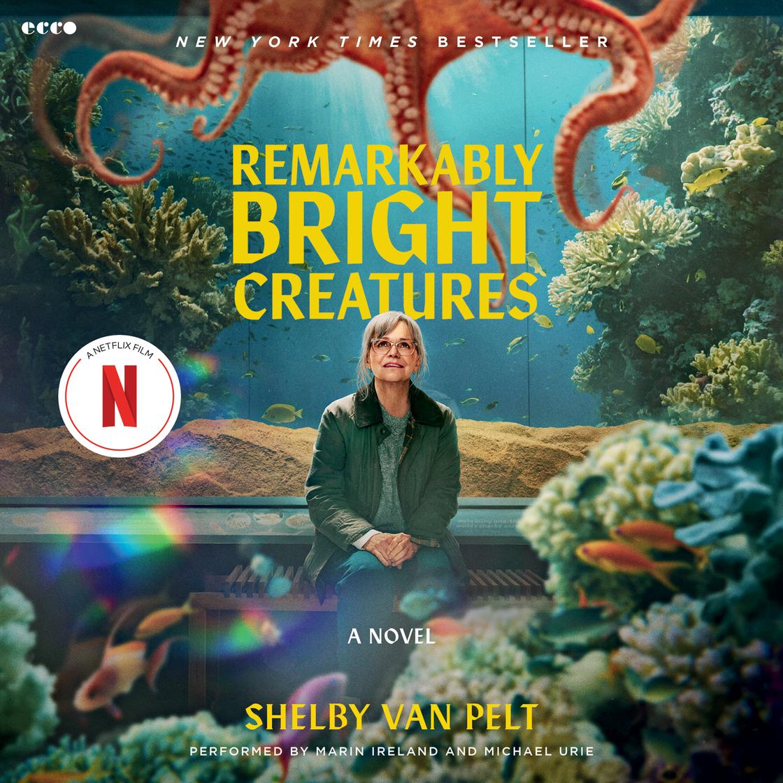 An underwater aquarium scene with coral and small fish. An older woman with glasses sits centered on a wooden bench in front of the tank. Above her, the orange arms of an octopus stretch across the top of the frame. The title is in bold yellow letters, and a red Netflix 'N' logo is featured on the left.