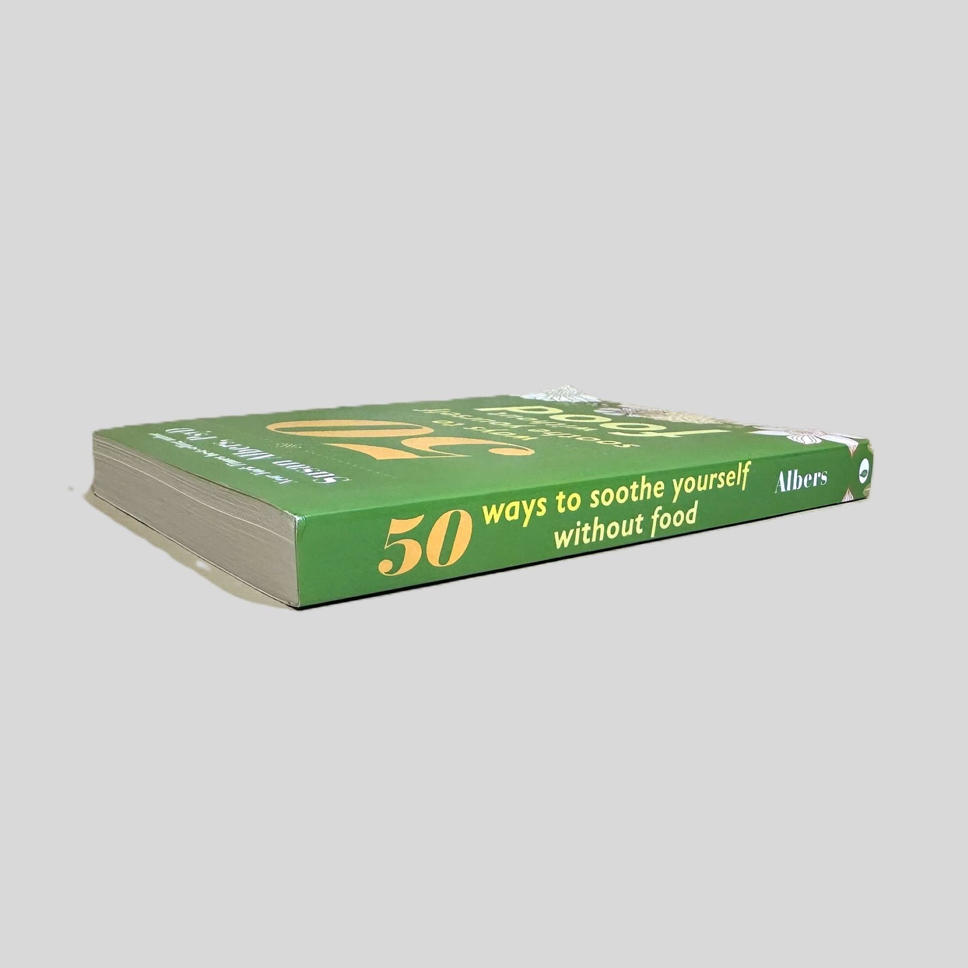 Spine of the 50 Ways to Soothe Yourself Without Food paperback. Displays the author and title in white and light yellow font against a solid green background. The visual confirms a Like New condition with a perfectly straight, uncreased spine.