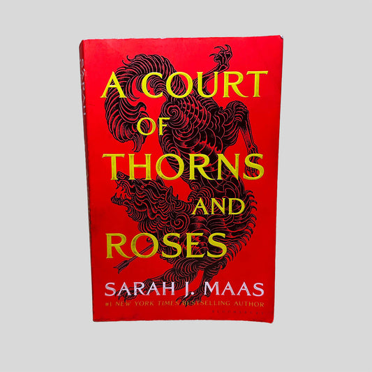 Front cover view of A Court of Thorns and Roses by Sarah J. Maas centered on a neutral light gray background. Creasing and minor chipping around the edges.