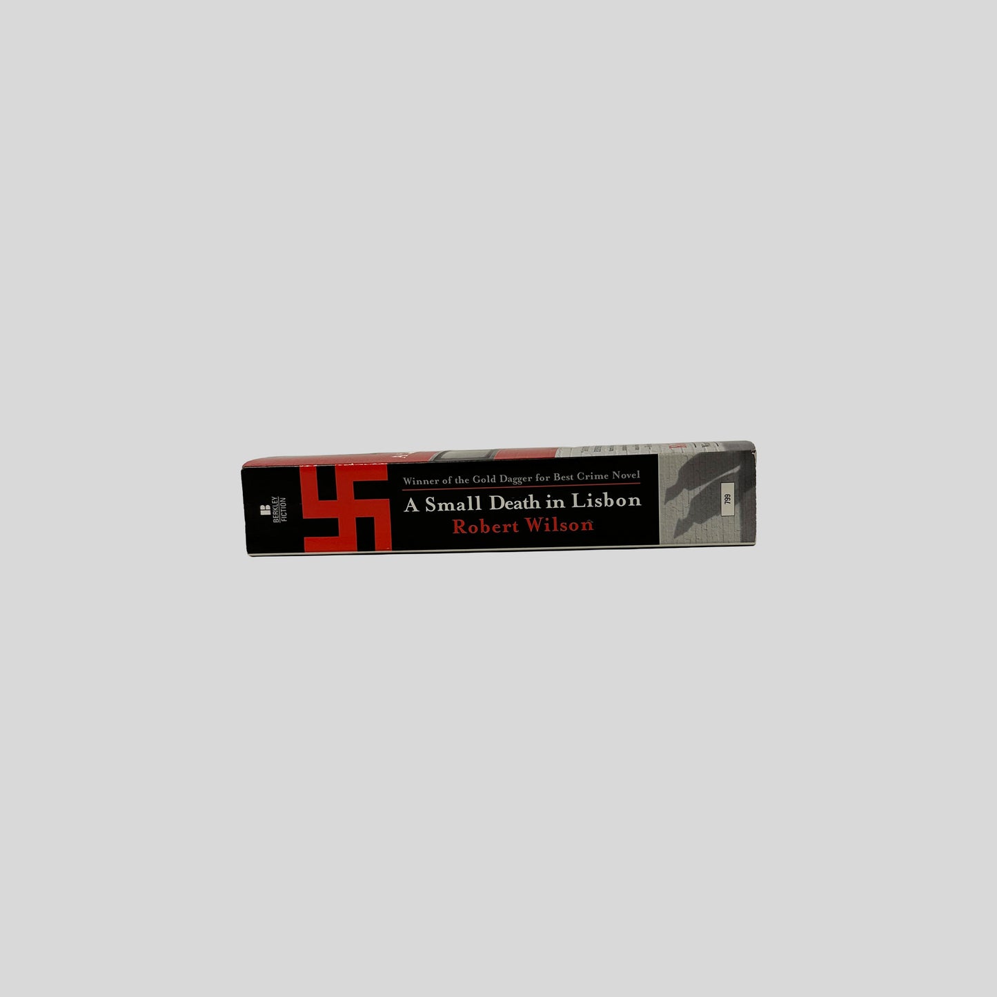 The spine of the book "A Small Death in Lisbon" by Robert Wilson, displaying a red swastika graphic and text noting it as the winner of the Gold Dagger for Best Crime Novel.