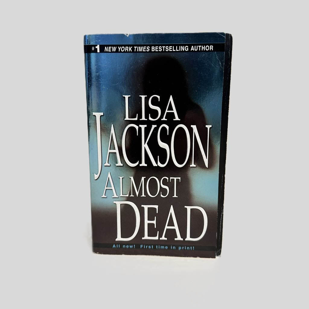 Front cover view of Almost Dead by Lisa Jackson centered on a neutral light gray background. Minimal creasing in the top corner.