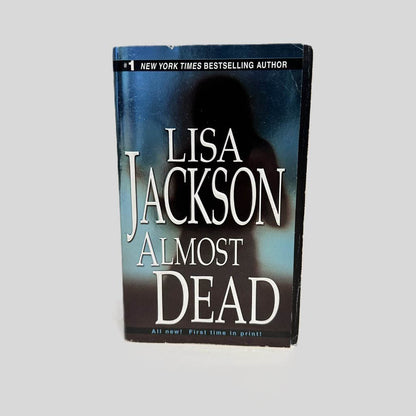 Front cover view of Almost Dead by Lisa Jackson centered on a neutral light gray background. Minimal creasing in the top corner.