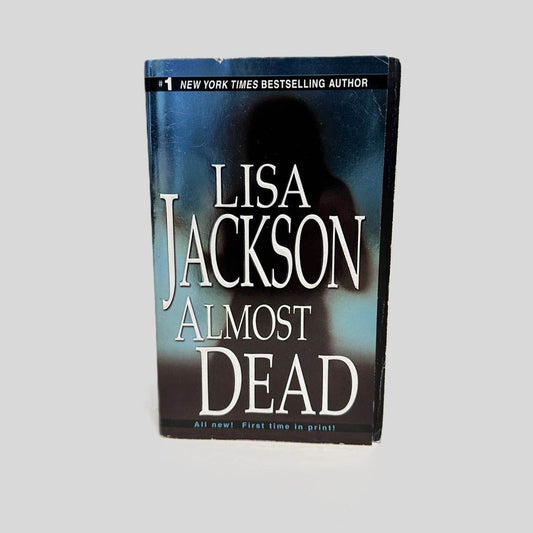 Front cover view of Almost Dead by Lisa Jackson centered on a neutral light gray background. Minimal creasing in the top corner.