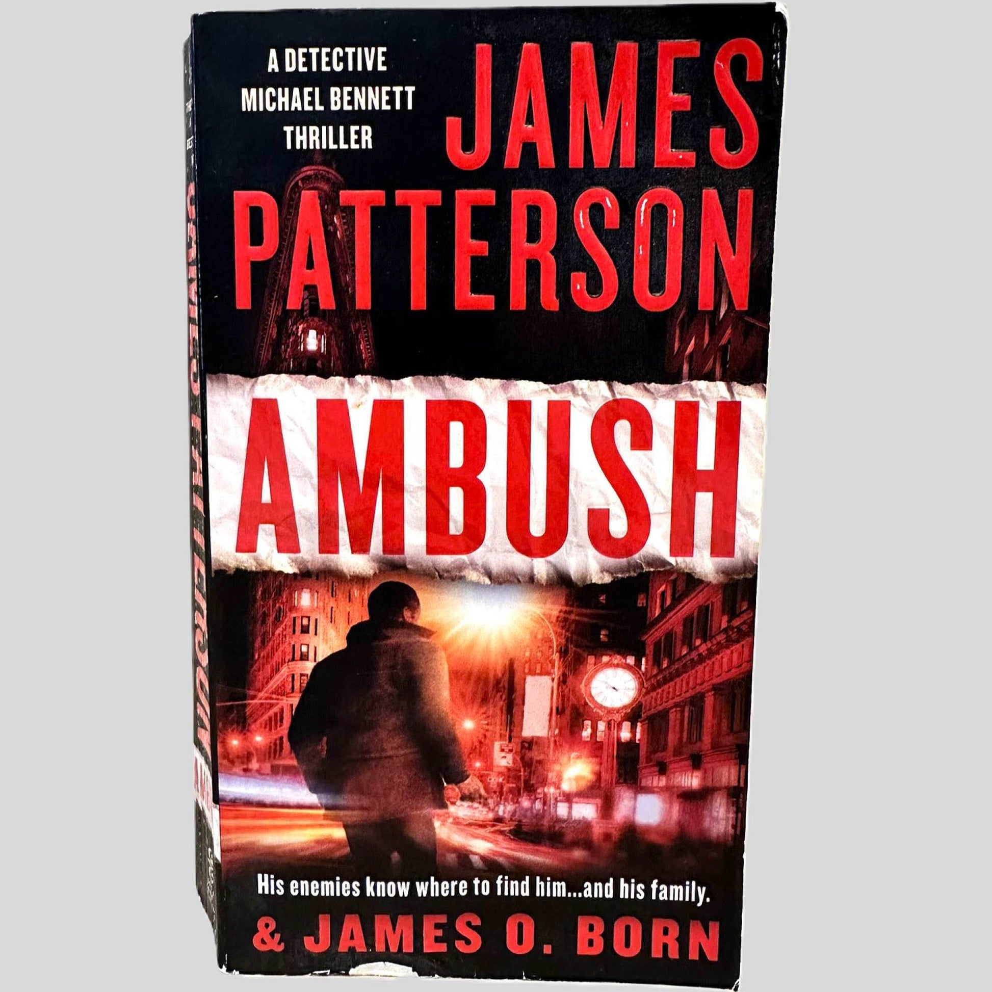 Front cover view of Ambush by James Patterson centered on a neutral light gray background. Chipping is present on the bottom edge and top corner of the front cover.