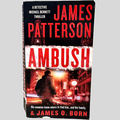 Front cover view of Ambush by James Patterson centered on a neutral light gray background. Chipping is present on the bottom edge and top corner of the front cover.