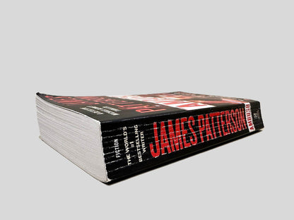 Close-up spine view of Ambush by James Patterson centered on a neutral light gray background. Spine shows creasing.