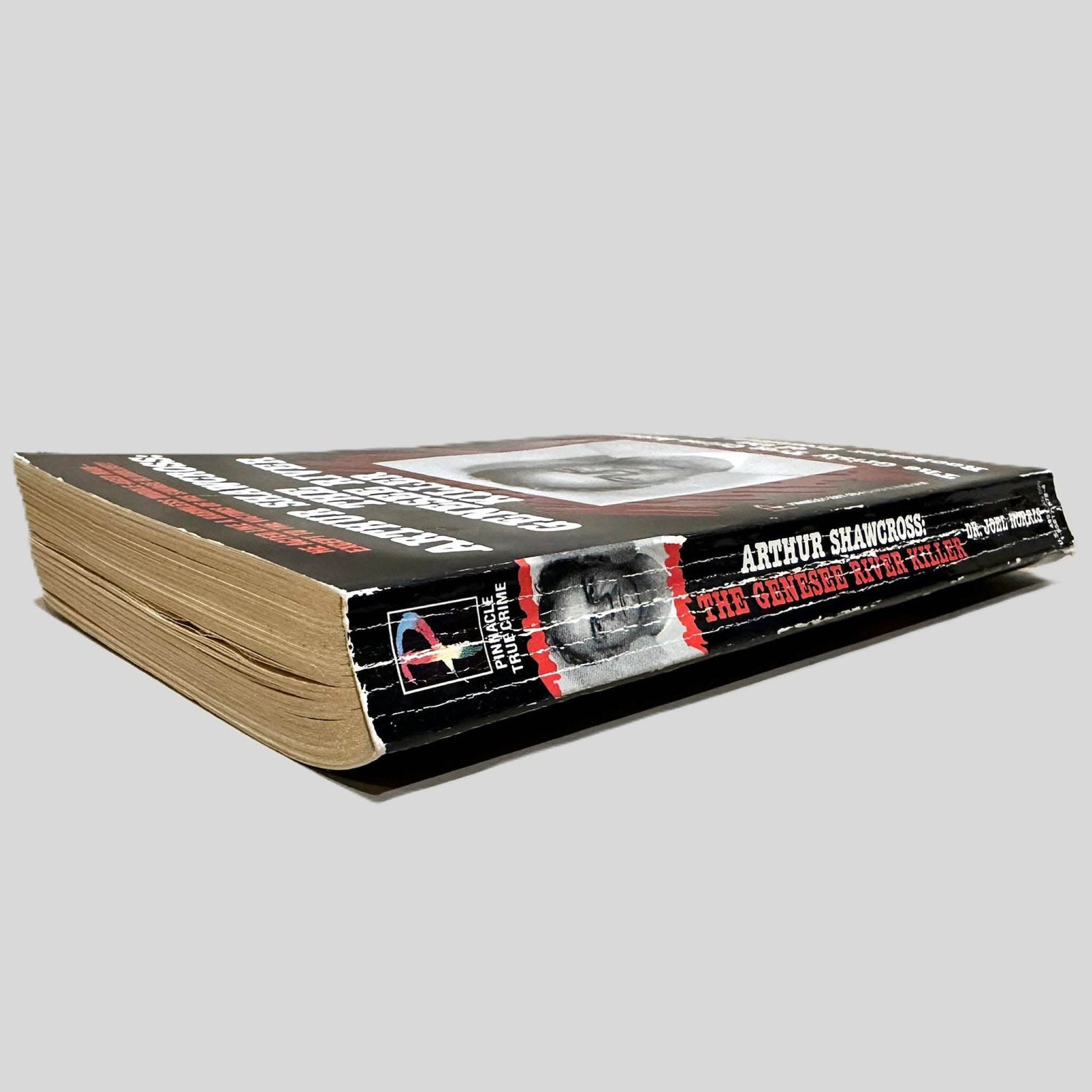 Close-up spine view of Arthur Shawcross: The Genesee River Killer by Dr. Joel Norris centered on a neutral light gray background. Spine shows cocking, creasing and rubbing.