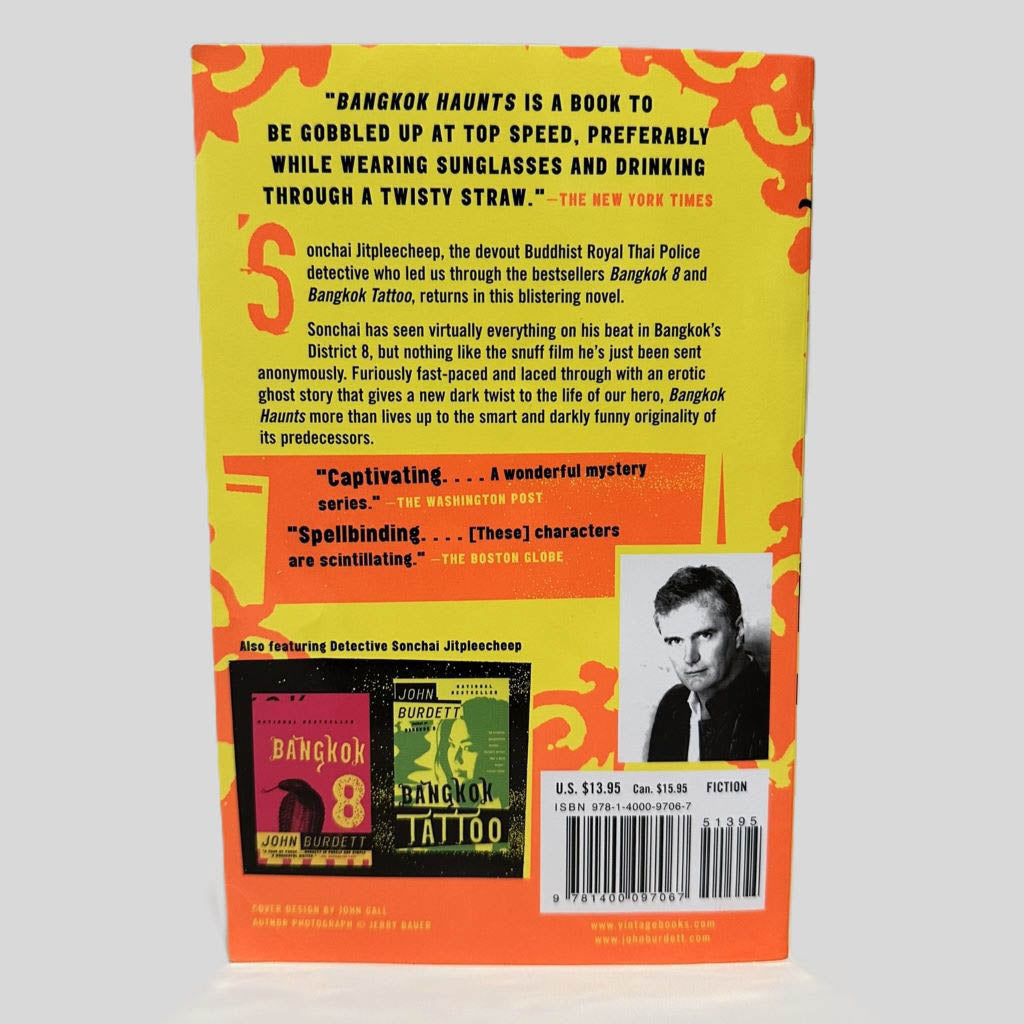 Back cover view of Bangkok Haunts by John Burdett centered on a neutral light gray background. Chipping along the top edge.