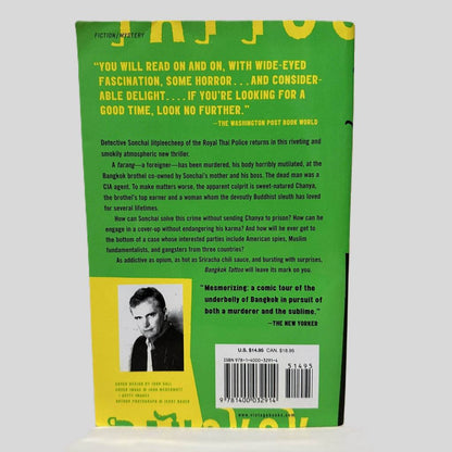 Back cover view of Bangkok Tattoo by John Burdett centered on a neutral light gray background. Chipping and creasing on the top left corner.