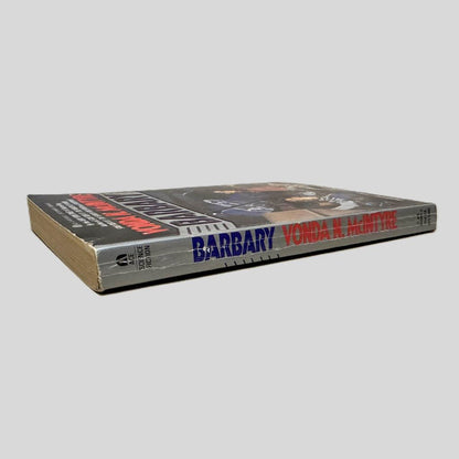 Close-up spine view of  centered on a neutral light gray background. Spine shows creasing. Pages lay flat.