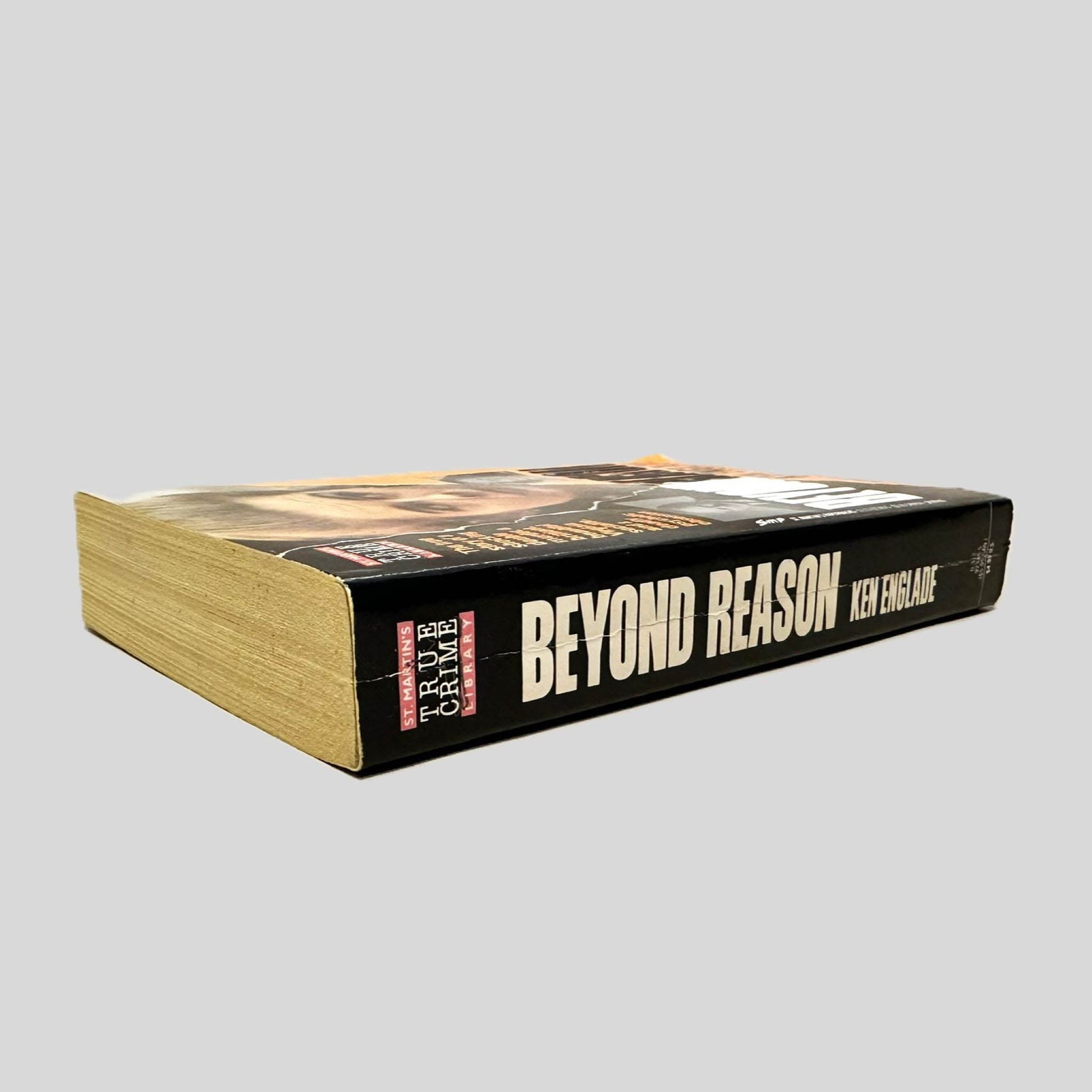 Close-up spine view of Beyond Reason by Ken Englade centered on a neutral light gray background. Spine shows creasing.