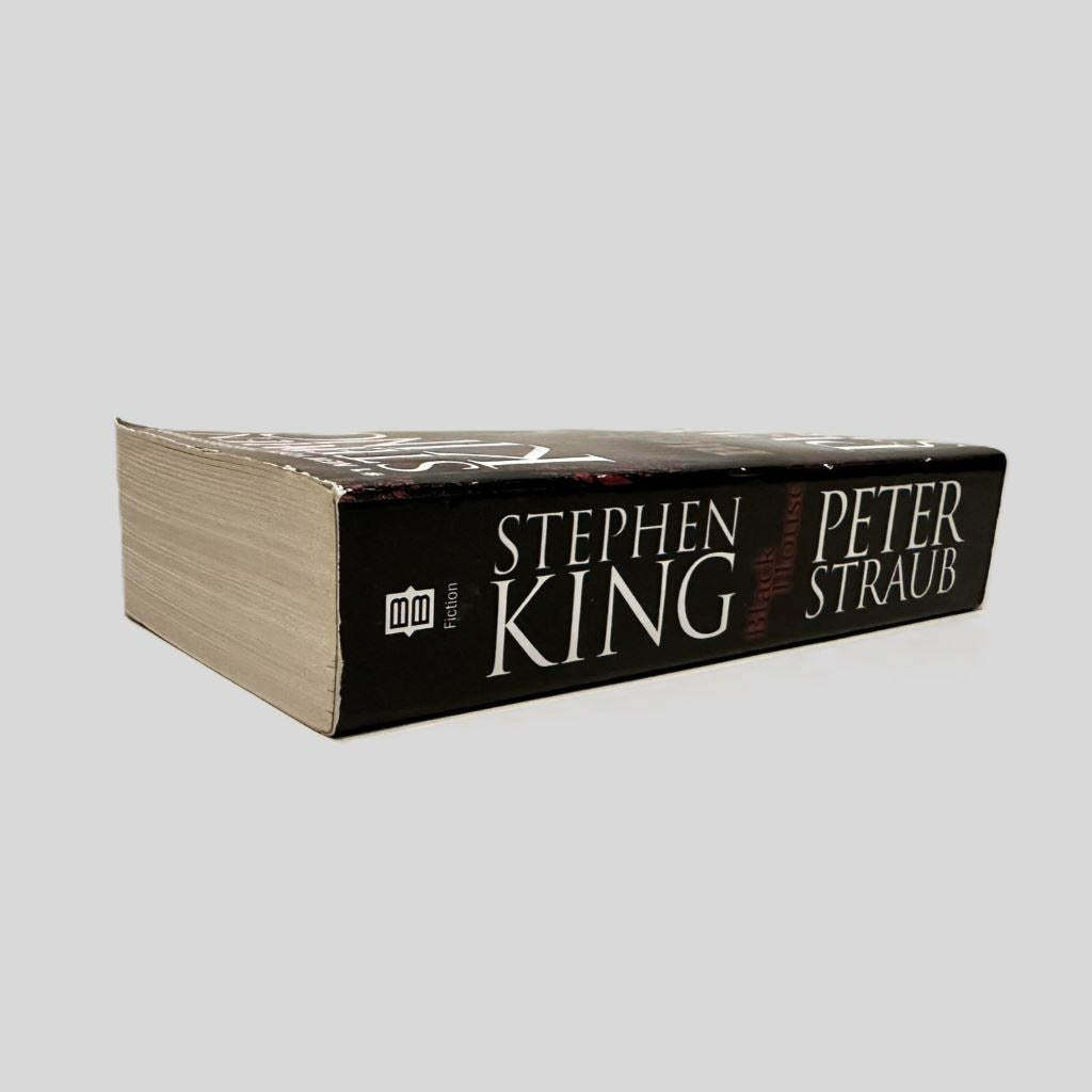 Close-up spine view of Black House by Stephen King and Peter Straub centered on a neutral light gray background. Spine shows minimal creasing. Pages lay flat.