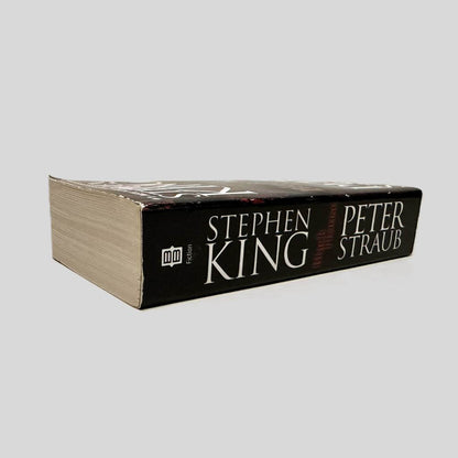 Close-up spine view of Black House by Stephen King and Peter Straub centered on a neutral light gray background. Spine shows minimal creasing. Pages lay flat.