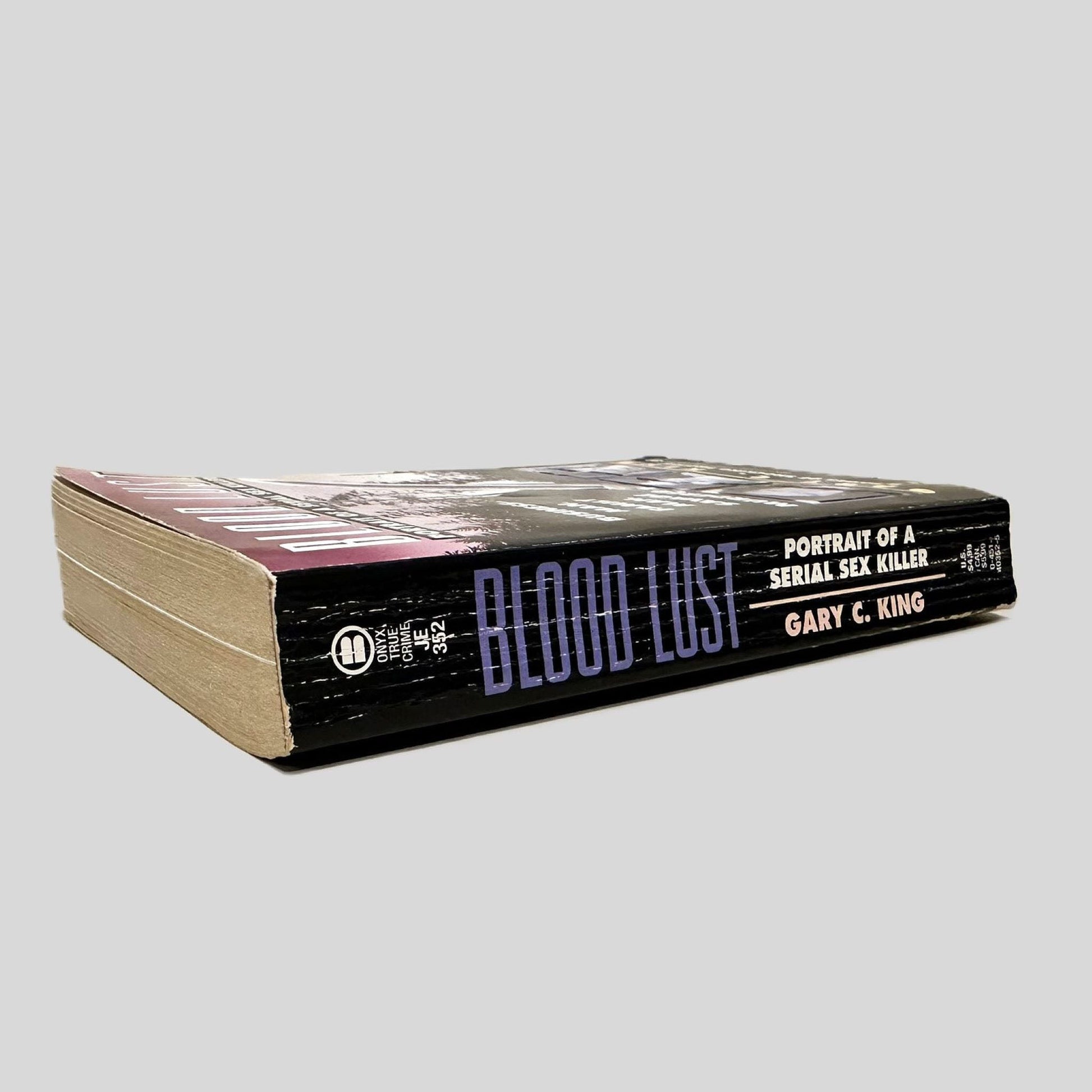 Close-up spine view of Blood Lust by Gary C. King centered on a neutral light gray background. Spine shows creasing and rubbing.