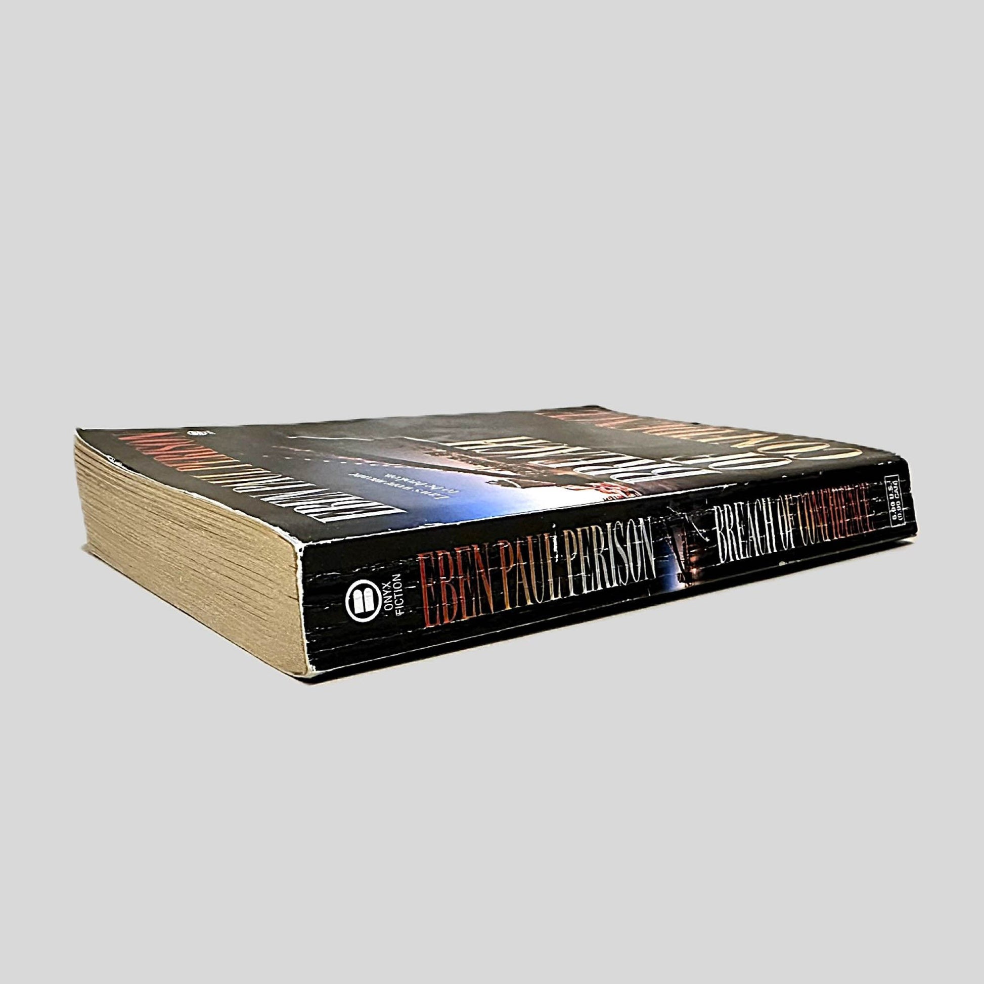 Close-up spine view of Breach of Confidence by Eben Paul Perison centered on a neutral light gray background. Spine shows creasing. Pages lay flat.