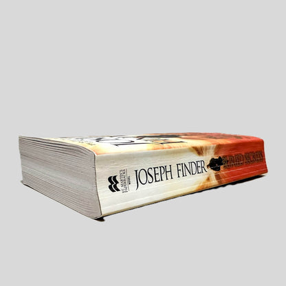 Close-up spine view of Buried Secrets by Joseph Finder centered on a neutral light gray background. Spine shows creasing.