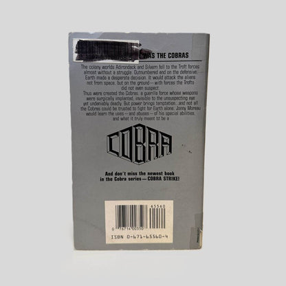 Back cover view of COBRA by Timothy Zahn centered on a neutral light gray background. Creasing at the top left corner. Library barcode sticker is also present in the top left corner, colored over with black ink. 
