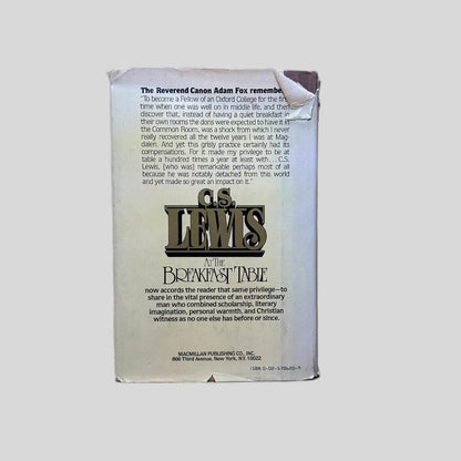Back cover view of C.S. Lewis At the Breakfast Table Edited by James T. Como centered on a neutral light gray background. Dust jacket is present. Significant tearing in the jacket in the top right corner. Tear in the jacket along the bottom edge and creasing to the top left corner. Hardcover book shows now damage.