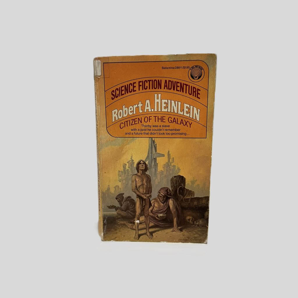 Front cover view of Starquake by Citizen of the Galaxy by Robert A. Heinlein centered on a neutral light gray background. Creasing is present near the spine. Chipping along the lower edge. Cover art is vibrant.