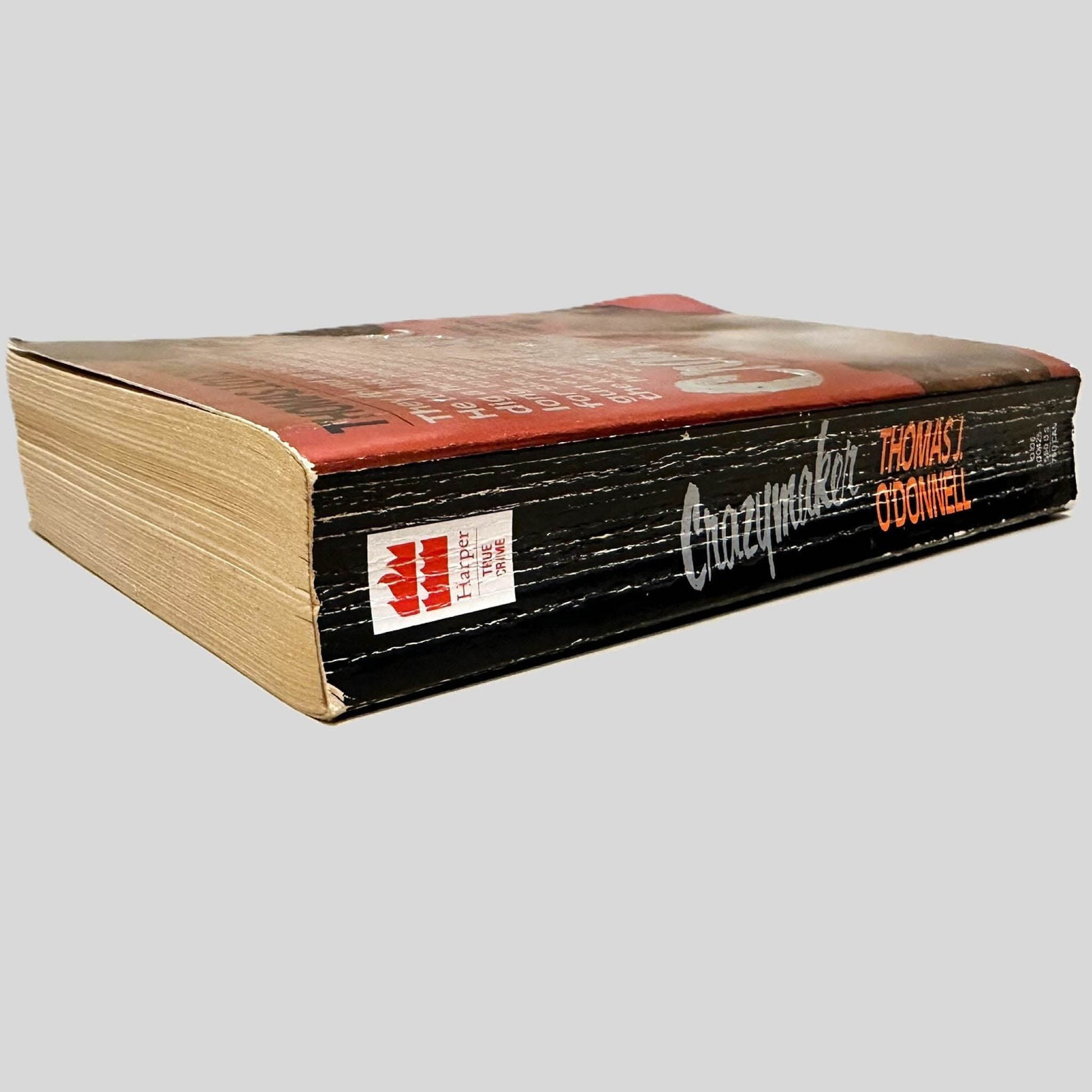 Close-up spine view of Crazymaker by Thomas J. O'Donnell centered on a neutral light gray background. Spine shows creasing and chipping.