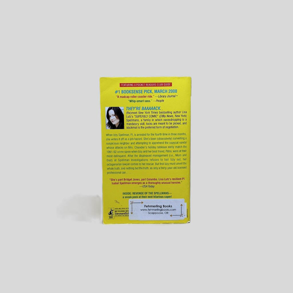 Back cover view of Curse of the Spellmans by Lisa Lutz centered on a neutral light gray background. Chipping present around the edges of the back cover. Creasing in the top left corner.