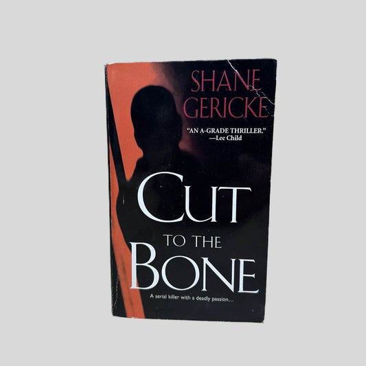 Front cover view of Cut to the Bone by Shane Gericke centered on a neutral light gray background. Top corner of front cover has a crease.