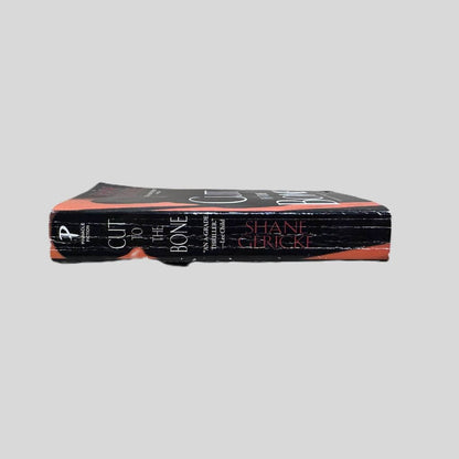 Close-up spine view of Cut to the Bone by Shane Gericke centered on a neutral light gray background. Spine shows creasing.