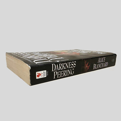 Close-up spine view of Darkness Peering by Alice Blanchard centered on a neutral light gray background. Spine shows minimal creasing. Pages lay flat.