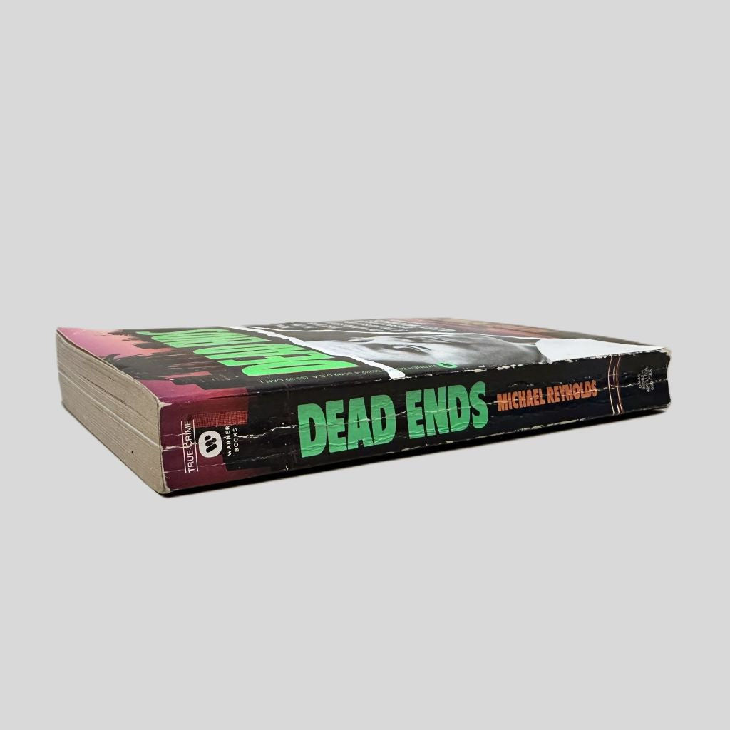 Close-up spine view of Dead Ends by Michael Reynolds centered on a neutral light gray background. Spine shows creasing and cocking.