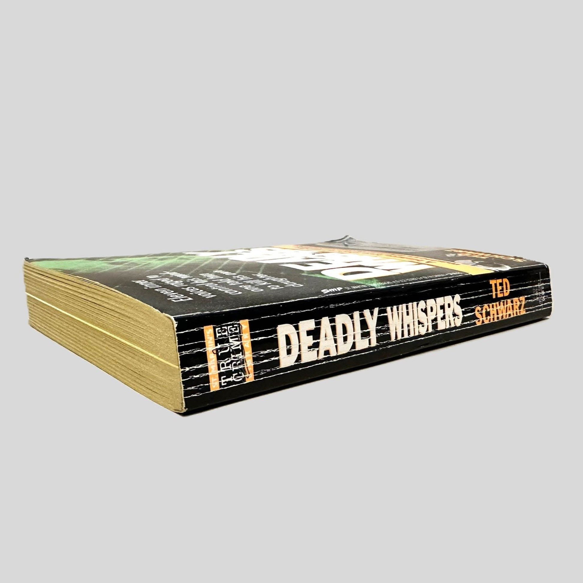 Close-up spine view of Deadly Whispers by Ted Schwarz centered on a neutral light gray background. Spine is square, shows creasing.