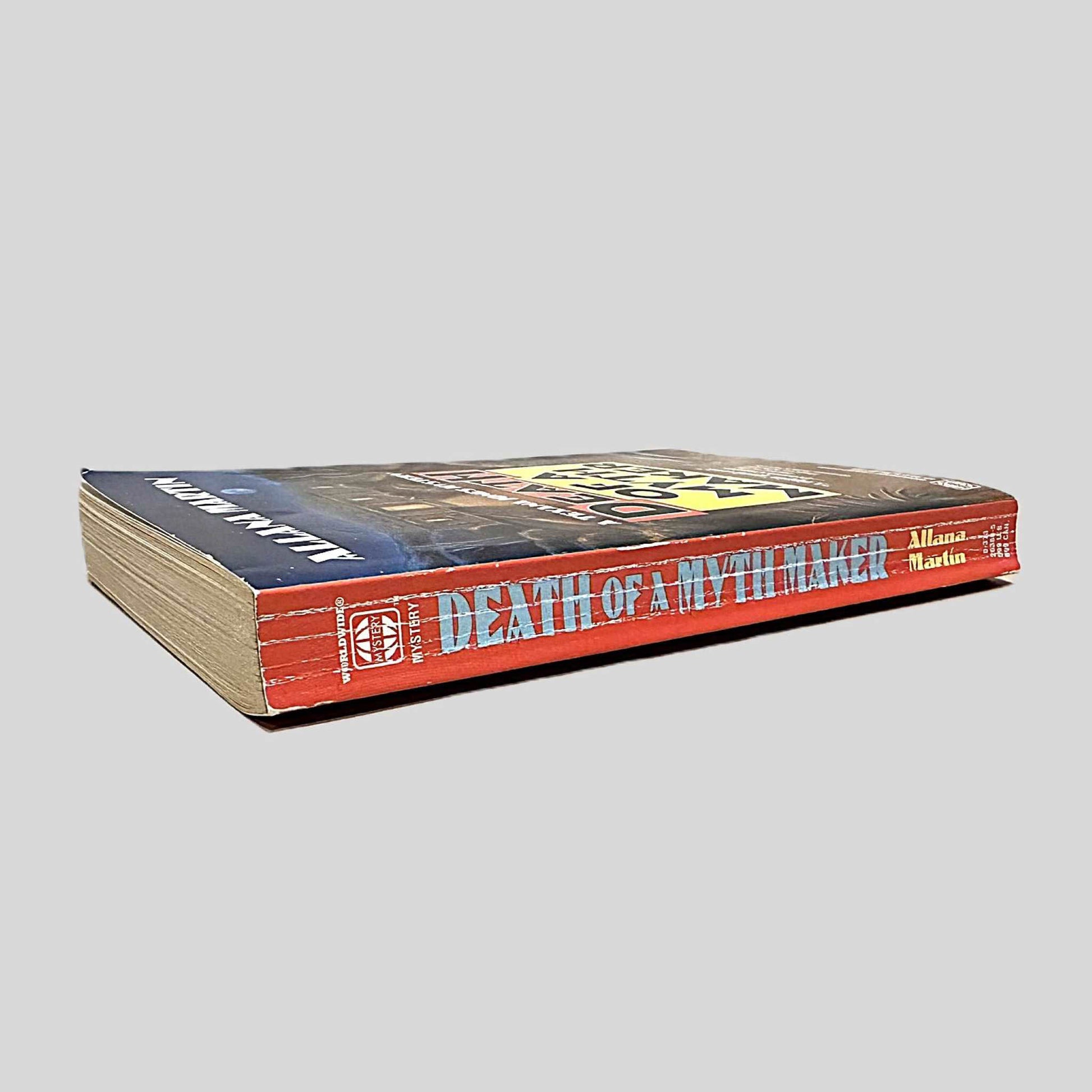 Close-up spine view of Death Of A Myth Maker by Allana Martin centered on a neutral light gray background. Spine shows creasing.