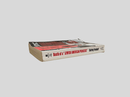 Close-up spine view of Death of a Jewish American Princess by Shirley Frondrof centered on a neutral light gray background. Spine shows creasing and rubbing.