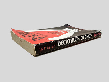 Close-up spine view of Decathlon of Death by Jack Leslie centered on a neutral light gray background. Spine shows rubbing and minimal creasing.