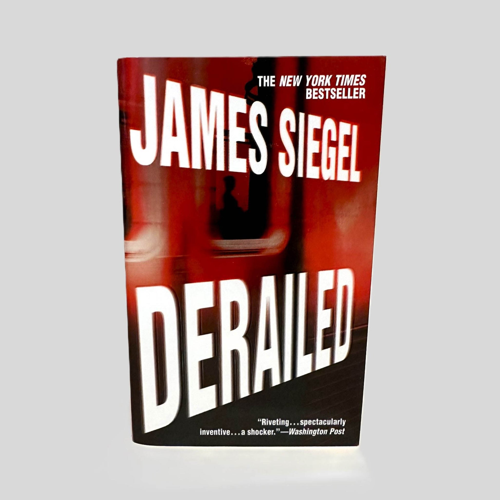Front cover view of Derailed by James Siegel centered on a neutral light gray background. 