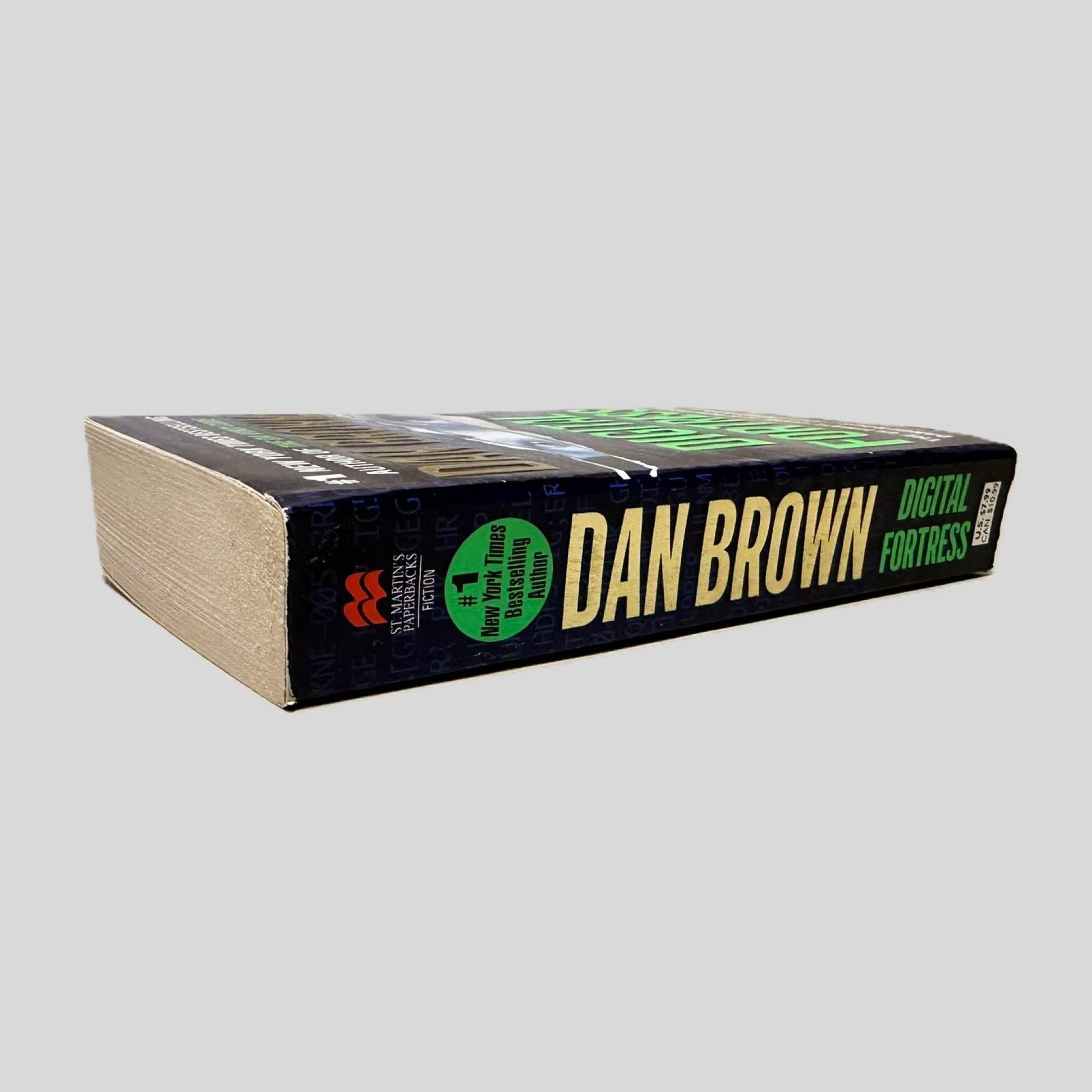 Close-up spine view of Digital Fortress by Dan Brown centered on a neutral light gray background. Spine is square and shows no creasing. Pages lay flat.