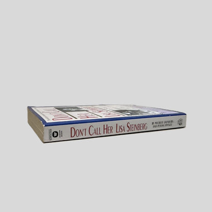 Close-up spine view of Don't Call Her Lisa Steinberg by Michele Launders & Panina Spiegel centered on a neutral light gray background. Spine is square and shows minimal creasing.