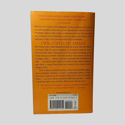 Back cover view of Dragonfly In Amber by Diana Gabaldon centered on a neutral light gray background. Minor chipping to the top right corner.