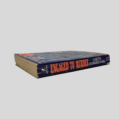 Close-up spine view of Engaged To Murder by Loretta Schwartz-Nobel centered on a neutral light gray background. Spine shows creasing and bumping.