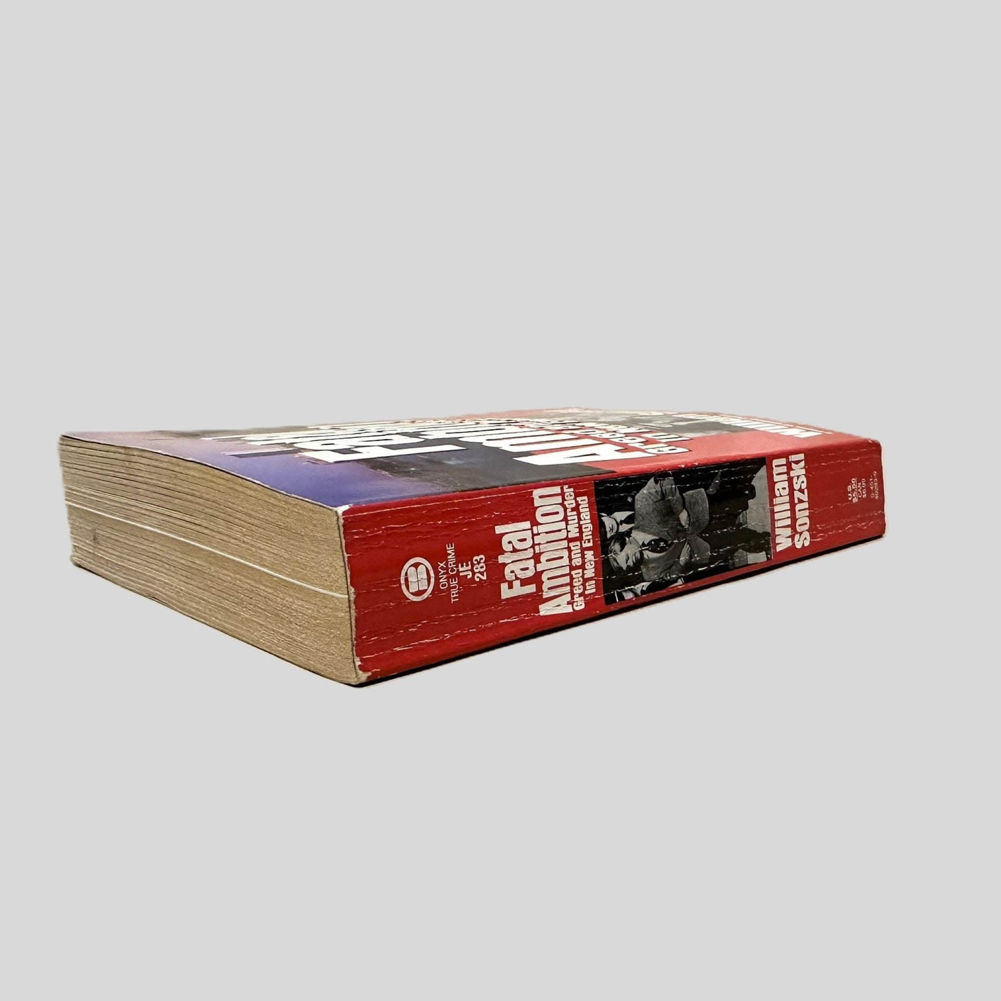 Close-up spine view of Fatal Ambition by William Sonzski centered on a neutral light gray background. Spine shows creasing.