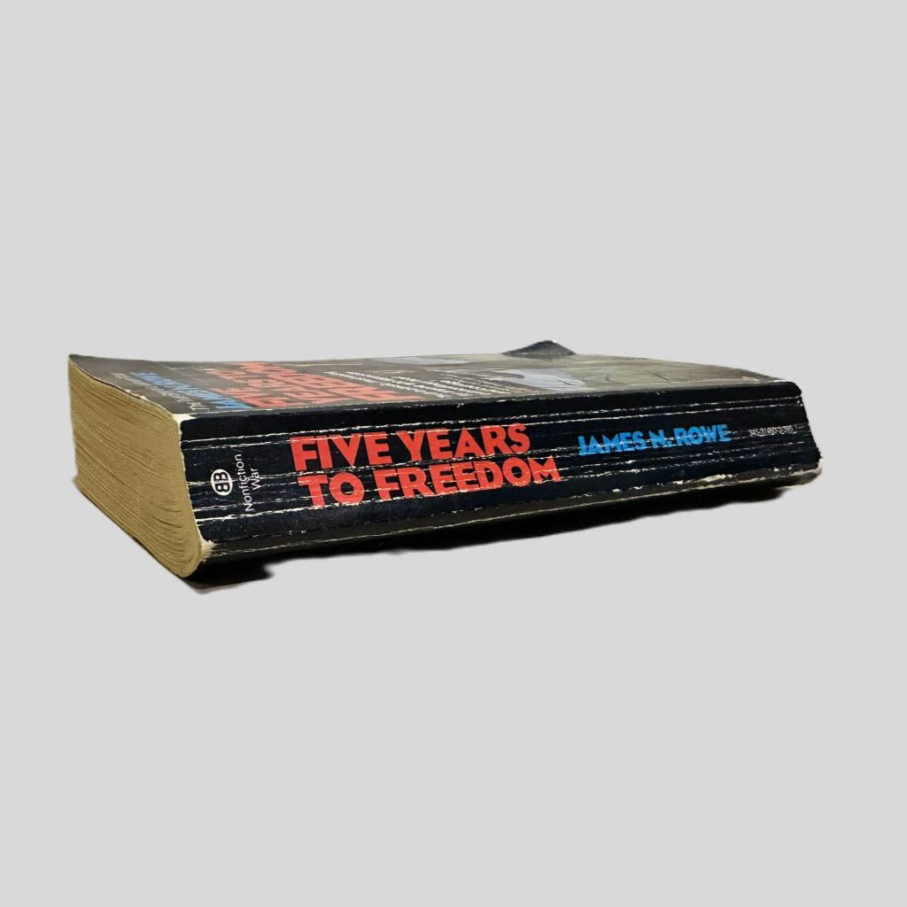 Close-up spine view of Five Years to Freedom: The True Story of a Vietnam POW by James N. Rowe centered on a neutral light gray background. Spine shows chipping and creasing. Pages lay flat.