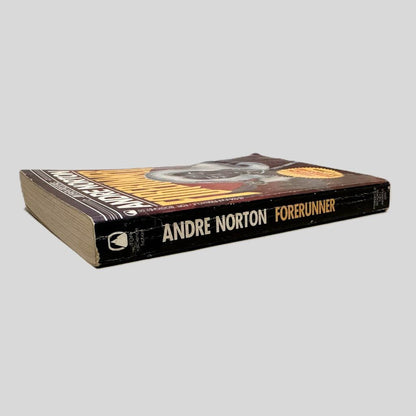 Close-up spine view of Forerunner by Andre Norton centered on a neutral light gray background. Spine shows normal chipping for age and creasing. Pages lay flat.