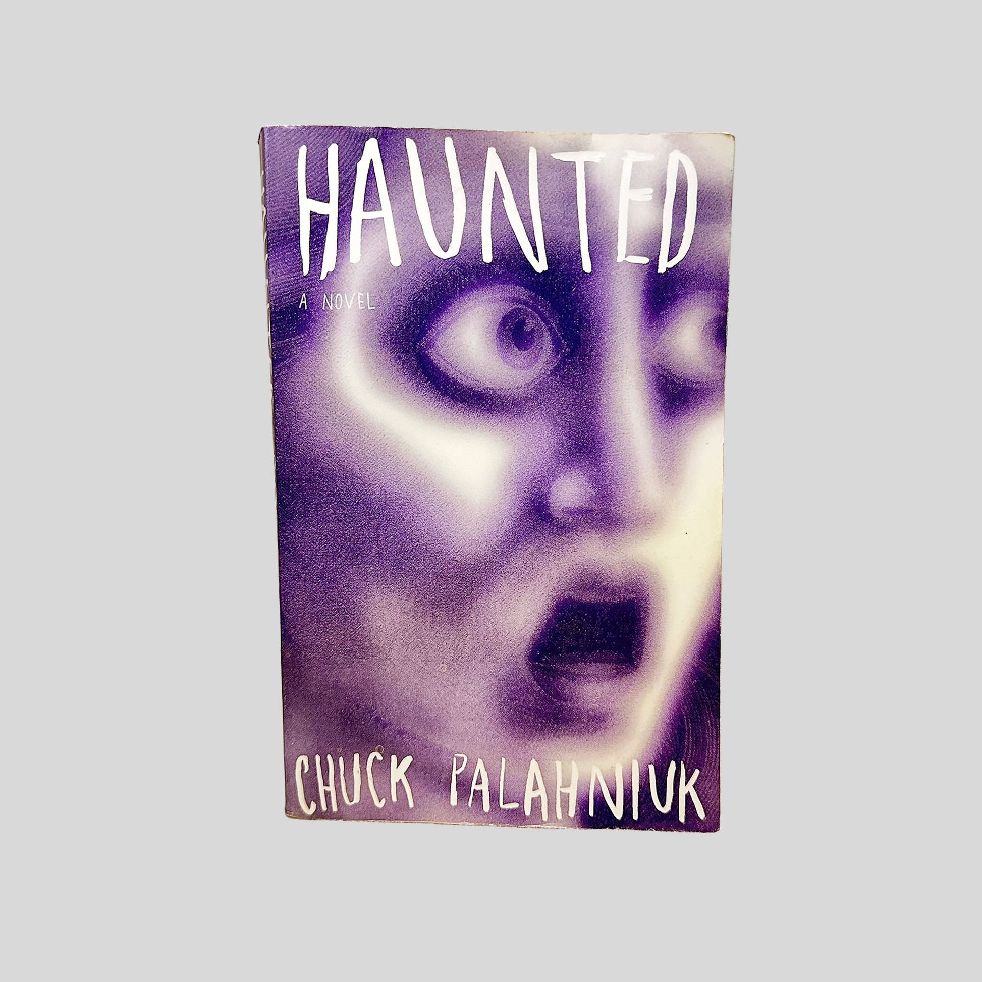 Front cover view of Haunted by Chuck Palahniuk centered on a neutral light gray background. 