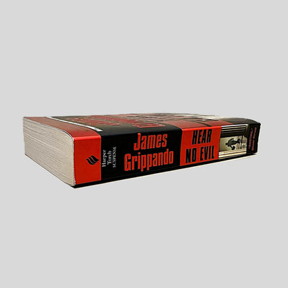 Close-up spine view of Hear No Evil by James Grippando centered on a neutral light gray background. Spine is square and no visible creasing.