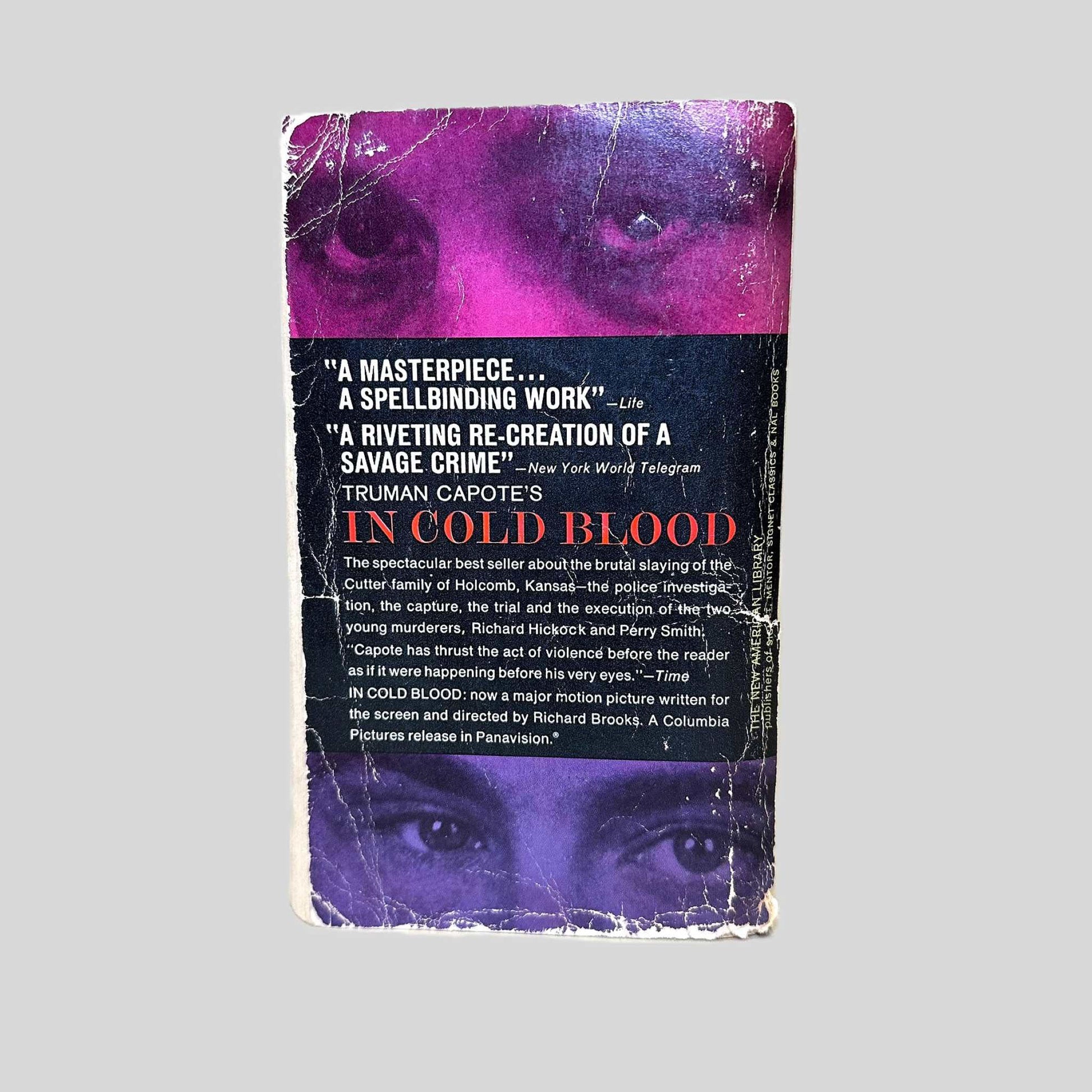 Back cover view of In Cold Blood by Truman Capote centered on a neutral light gray background. The back cover shows wear from age with rubbing and bumping present.