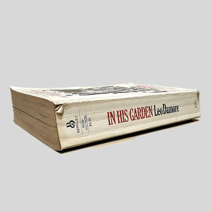 Close-up spine view of In His Garden by Leo Damore centered on a neutral light gray background. Spine is square with bumping and creasing.