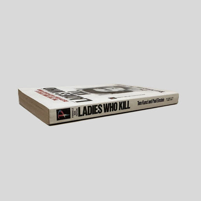 Close-up spine view of Ladies Who Kill by Tom Kuncl & Paul Einstein centered on a neutral light gray background. Spine is square and minimal creasing.