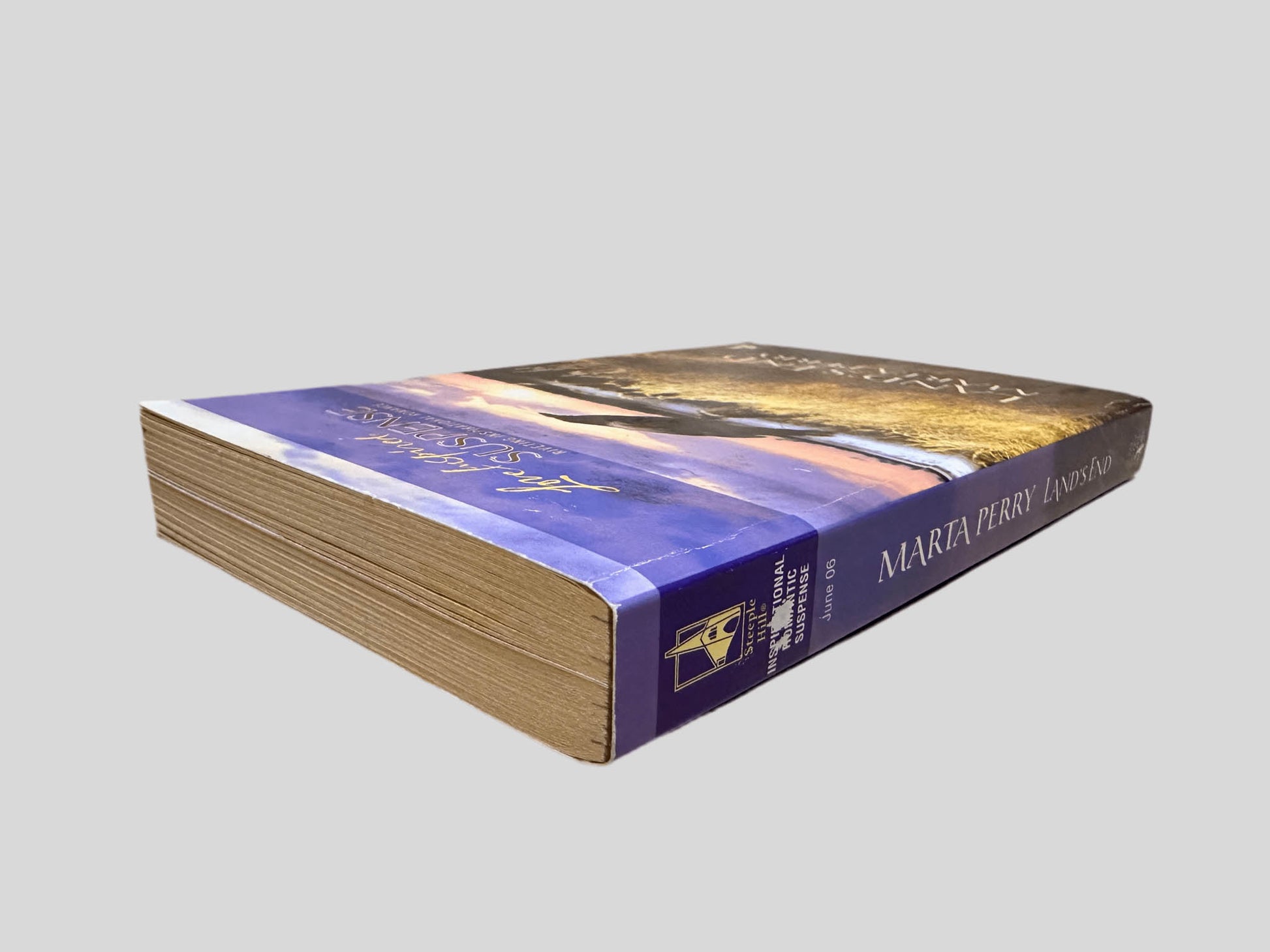 Close-up spine view of Land's End by Marta Perry centered on a neutral light gray background. Spine shows minimal creasing. Pages lay flat.