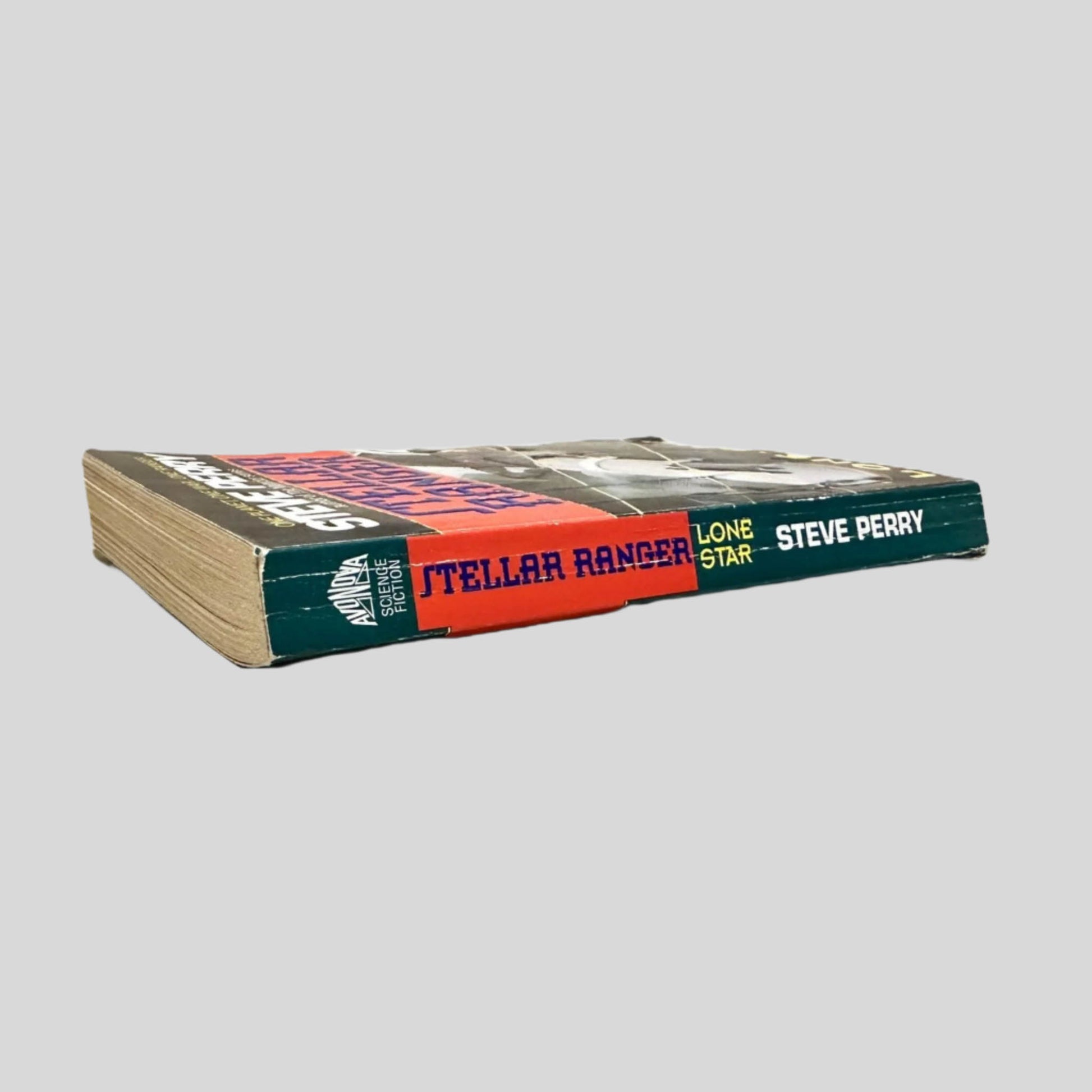 Close-up spine view of Lone Star by Steve Perry centered on a neutral light gray background. Spine shows creasing. Chipping on the bottom corner of spine. Pages lay flat.