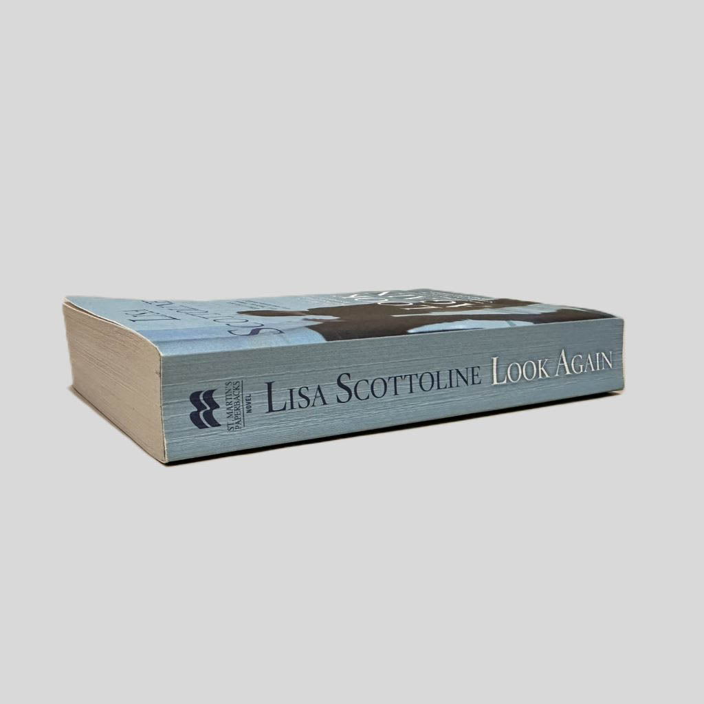 Close-up spine view of Look Again by Lisa Scottoline centered on a neutral light gray background. Spine is square and shows minimal creasing. Pages lay flat.
